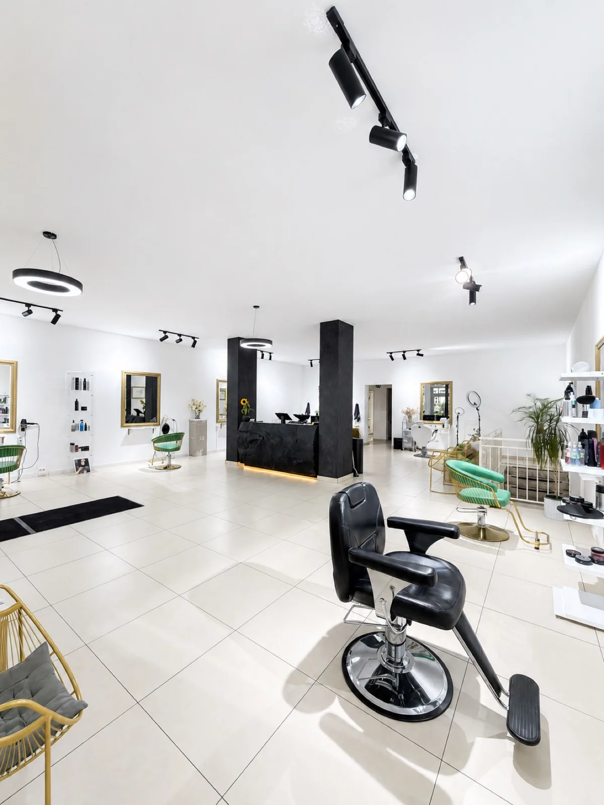 Innenraum des Friseursalons La Coiffeur in München-Neuperlach mit klassischem Barber-Stuhl, grün-goldenen Designer-Stühlen und schwarzer Empfangstheke